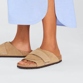 Beige Birkenstock Kyoto slides with embossed suede and adjustable hook-and-loop straps.