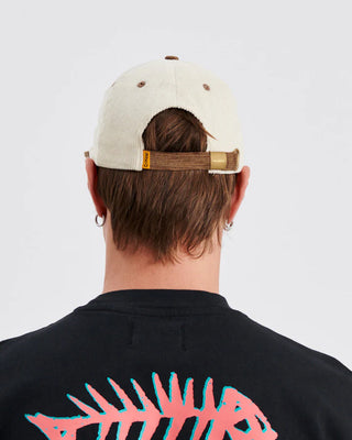 Ecru flat-brim cap with contrast brim and snapback closure.