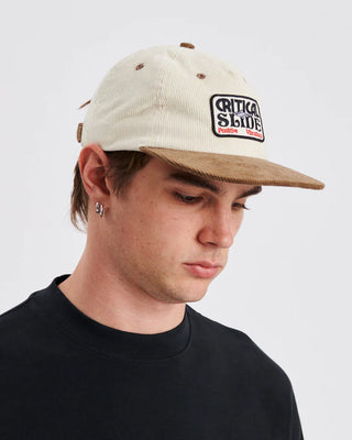 Ecru flat-brim cap with contrast brim and snapback closure.