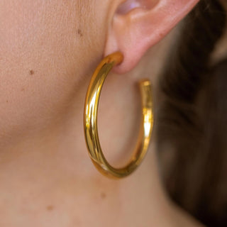 Gold hoop earrings with 18K plating, hypoallergenic, push-back clasp, and water-resistant.