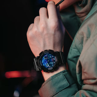 G-SHOCK GA100RGB-1A watch with glossy black bezel, multicolored face, and LED light.